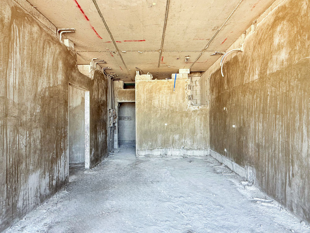 Beach Walk Iii By Imtiaz An unfinished interior space with bare, dust-covered walls and floor, showing exposed utilities and debris.